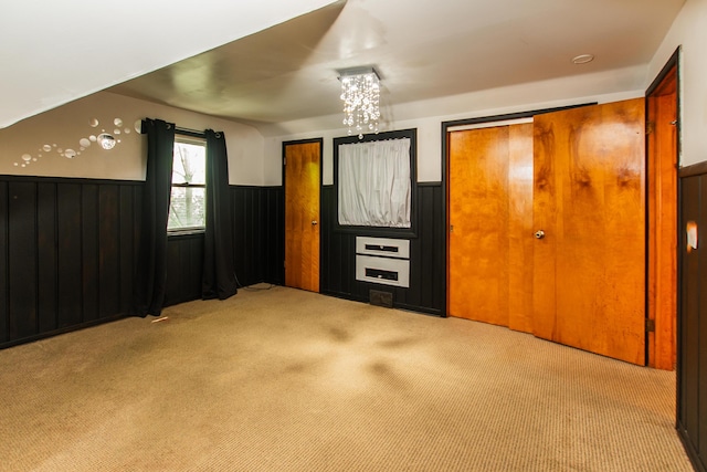 unfurnished bedroom featuring carpet floors, a notable chandelier, and a wainscoted wall