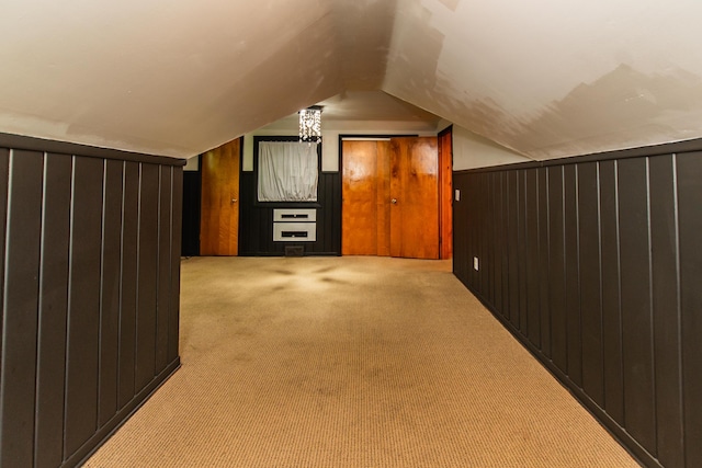 additional living space featuring wooden walls, vaulted ceiling, and light colored carpet