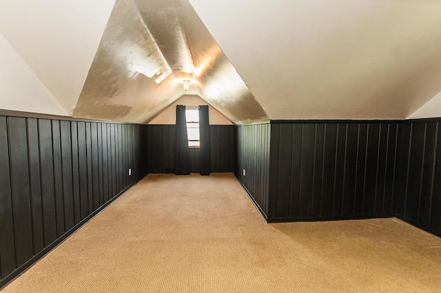 additional living space with wood walls, lofted ceiling, and light carpet