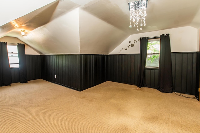 bonus room with wainscoting, lofted ceiling, and light carpet