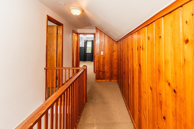corridor with carpet floors, vaulted ceiling, and an upstairs landing