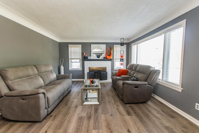 living area featuring baseboards, a textured ceiling, wood finished floors, and a fireplace