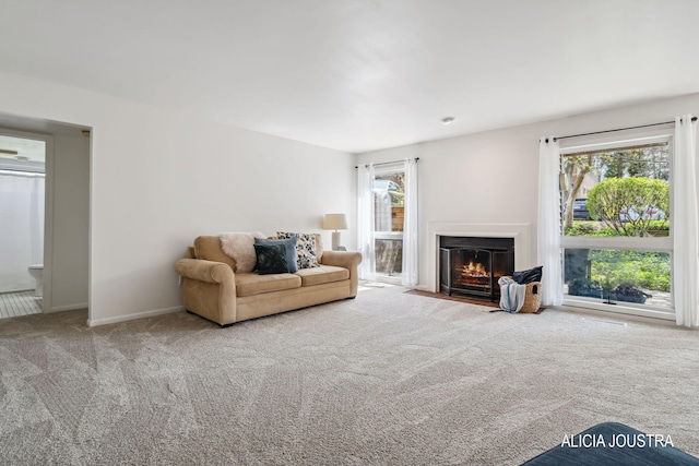 carpeted living room featuring baseboards and a fireplace with flush hearth
