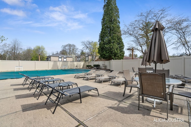 community pool with a patio and fence