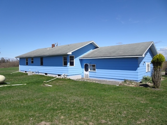 view of front of house featuring a chimney, roof with shingles, and a front lawn