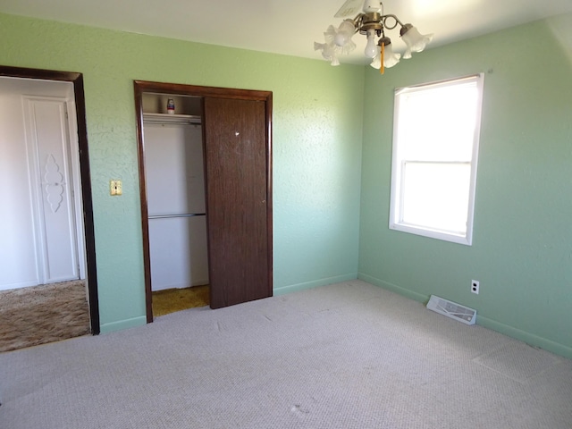 unfurnished bedroom featuring visible vents, carpet, baseboards, and a closet