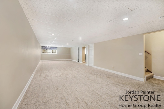 below grade area with stairway, carpet flooring, and a drop ceiling