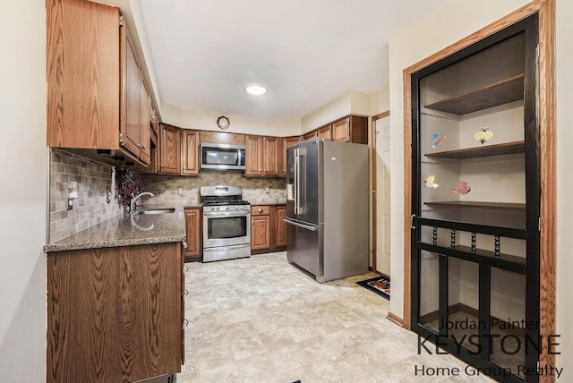 kitchen with brown cabinets, a sink, stainless steel appliances, stone counters, and decorative backsplash