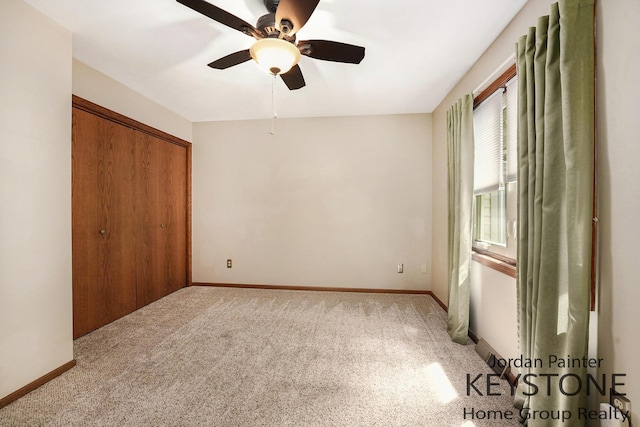 unfurnished bedroom with baseboards, ceiling fan, carpet, and a closet
