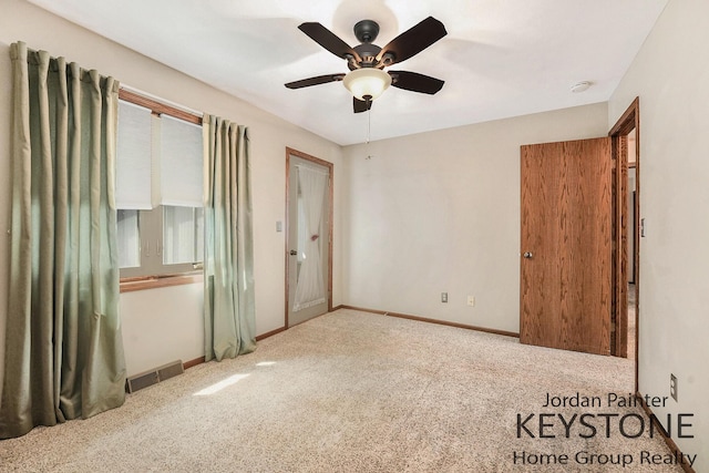 carpeted spare room with a ceiling fan, baseboards, and visible vents