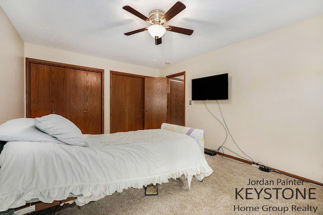 bedroom featuring baseboards, carpet flooring, multiple closets, and a ceiling fan