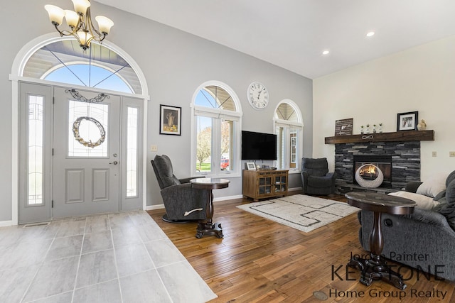 foyer featuring a fireplace, a chandelier, a healthy amount of sunlight, and wood finished floors