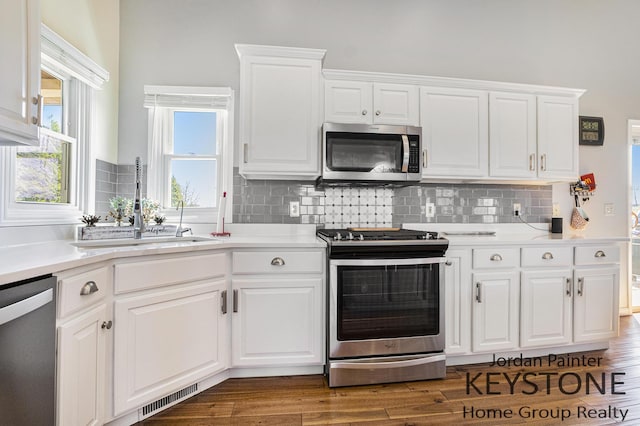 kitchen featuring a sink, appliances with stainless steel finishes, decorative backsplash, and light countertops