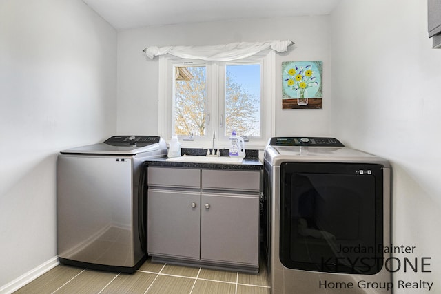 washroom featuring separate washer and dryer, a sink, cabinet space, and baseboards