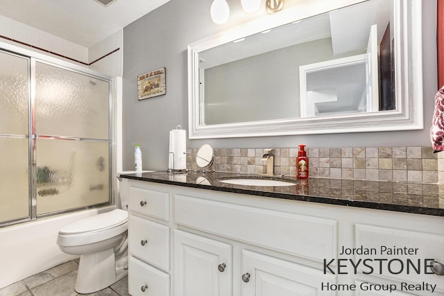 full bath featuring vanity, decorative backsplash, tile patterned flooring, toilet, and combined bath / shower with glass door