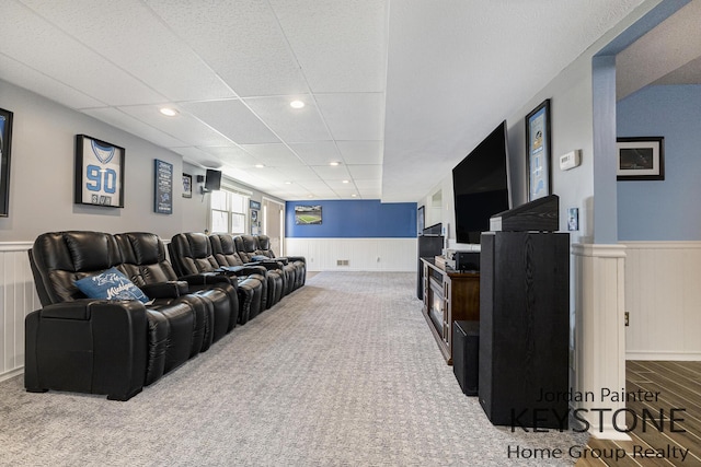 carpeted cinema room featuring recessed lighting, a paneled ceiling, a decorative wall, and a wainscoted wall