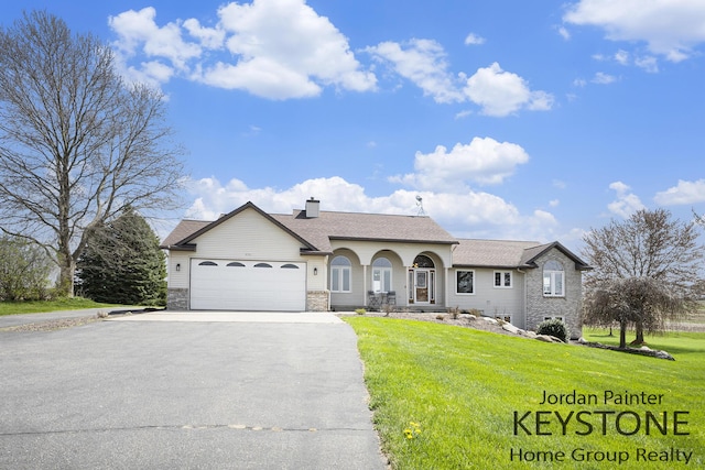 single story home featuring a shingled roof, a garage, a front yard, a chimney, and driveway