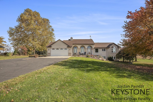 view of front of property with an attached garage, a chimney, a front lawn, and aphalt driveway