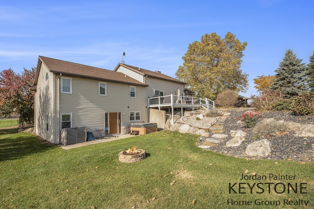 rear view of property with an outdoor fire pit, a wooden deck, a patio area, a hot tub, and a yard