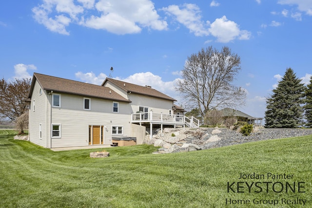 rear view of property featuring a hot tub, a yard, and a wooden deck