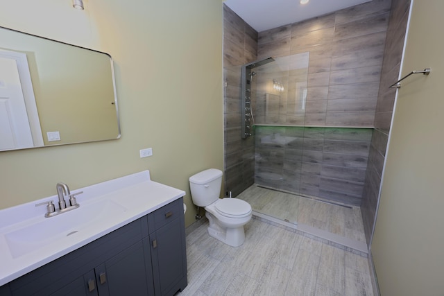 bathroom with vanity, a tile shower, and toilet