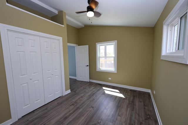 unfurnished bedroom with a closet, lofted ceiling, baseboards, ceiling fan, and dark wood-type flooring