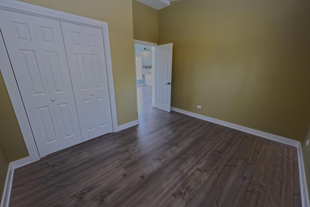 unfurnished bedroom featuring baseboards, a closet, and dark wood finished floors