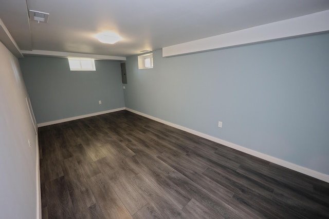 basement with baseboards, dark wood-type flooring, and visible vents