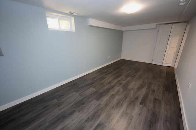 basement featuring visible vents, dark wood finished floors, and baseboards