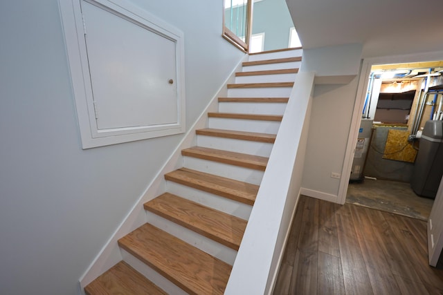 stairway featuring baseboards, water heater, and hardwood / wood-style floors