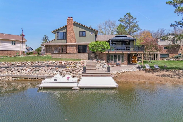 view of dock with a patio, a lawn, and a deck with water view