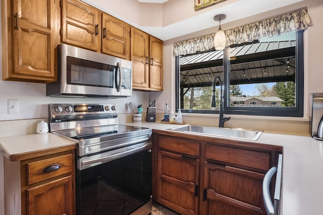 kitchen featuring light countertops, brown cabinets, appliances with stainless steel finishes, and a sink