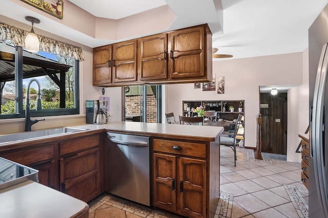 kitchen featuring stainless steel dishwasher, a sink, light tile patterned floors, light countertops, and a peninsula