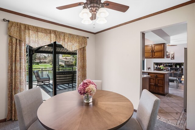 dining space featuring crown molding, a ceiling fan, baseboards, and light tile patterned floors