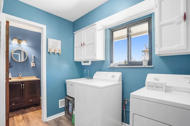 laundry area featuring light wood-style floors, cabinet space, washing machine and dryer, and visible vents