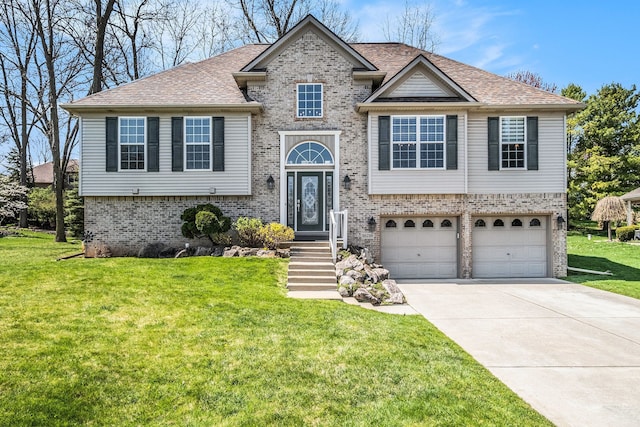 bi-level home with a garage, a front yard, brick siding, a shingled roof, and concrete driveway