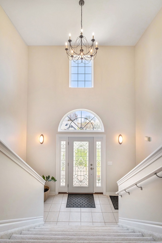 foyer featuring light tile patterned floors, baseboards, stairway, and a notable chandelier