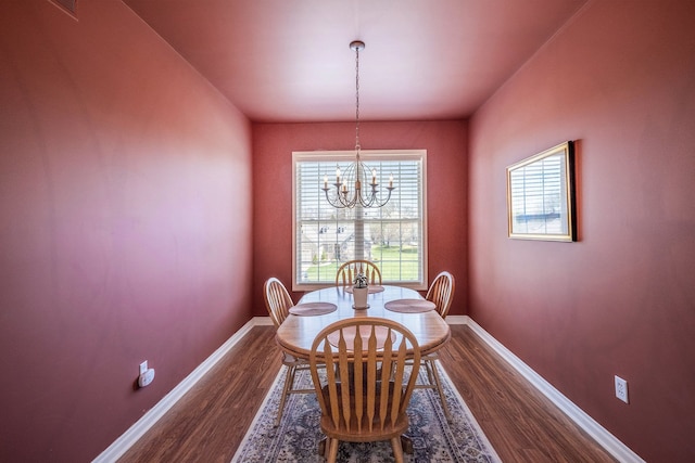 dining space with an inviting chandelier, baseboards, and dark wood-type flooring