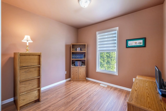 unfurnished office with baseboards, wood finished floors, and visible vents