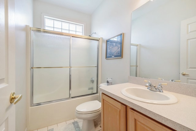 bathroom featuring vanity, enclosed tub / shower combo, tile patterned floors, and toilet