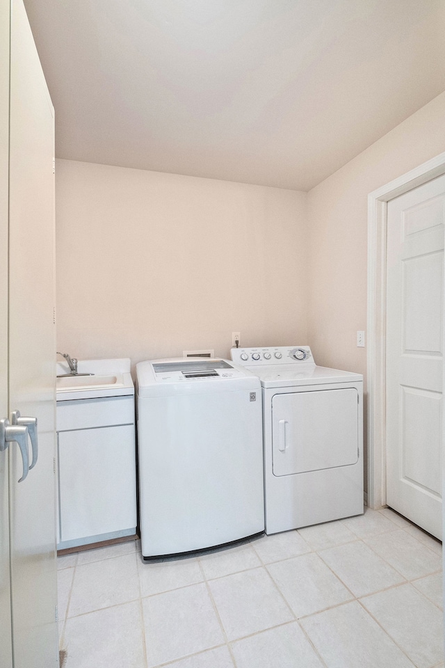 washroom featuring a sink, cabinet space, light tile patterned flooring, and washer and dryer