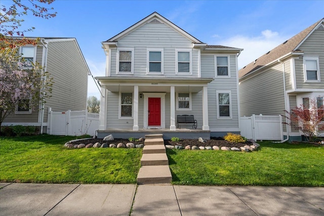traditional-style house featuring a porch, a gate, fence, and a front yard