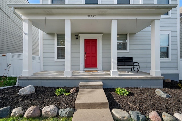 doorway to property featuring covered porch and fence