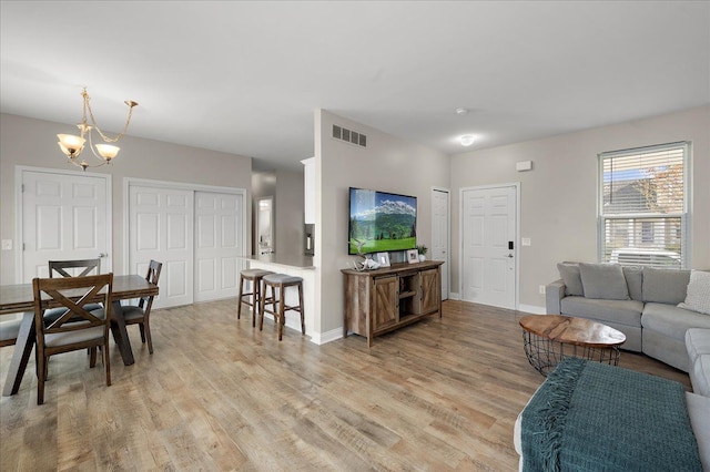 living room with light wood-style floors, baseboards, a notable chandelier, and visible vents