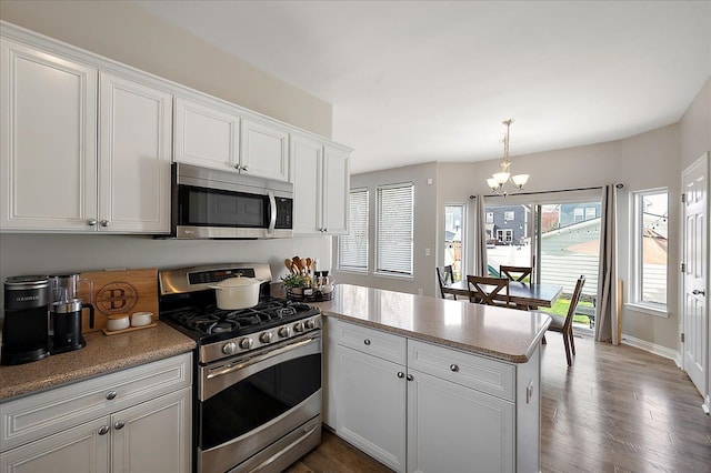 kitchen with appliances with stainless steel finishes, light countertops, a chandelier, a peninsula, and white cabinetry