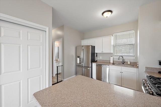 kitchen featuring a sink, light countertops, stainless steel appliances, and white cabinetry