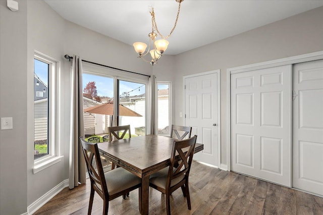 dining room featuring an inviting chandelier, a healthy amount of sunlight, baseboards, and dark wood-type flooring
