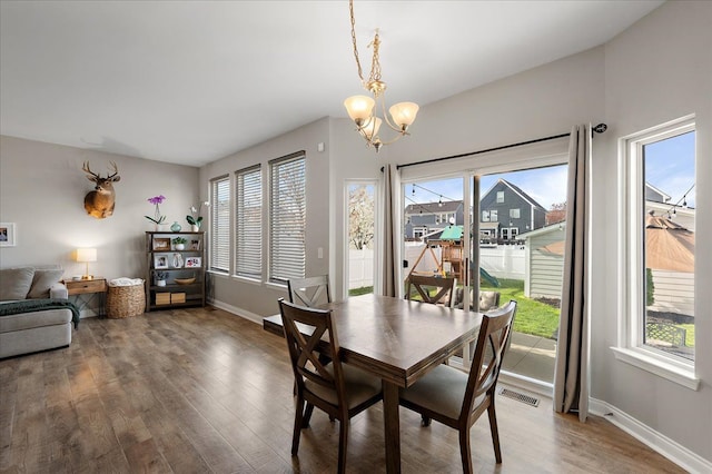 dining space featuring an inviting chandelier, baseboards, wood finished floors, and visible vents