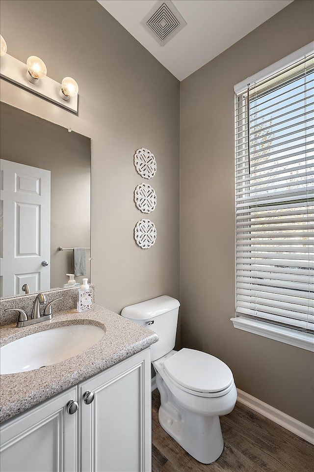 bathroom with visible vents, wood finished floors, vanity, baseboards, and toilet