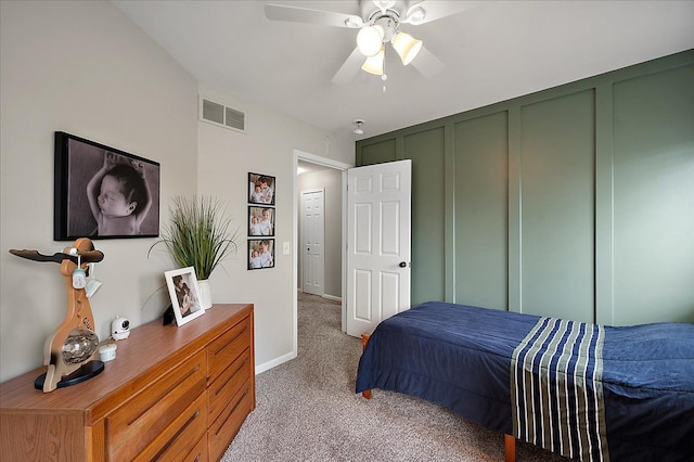 bedroom with a ceiling fan, visible vents, baseboards, carpet, and a decorative wall